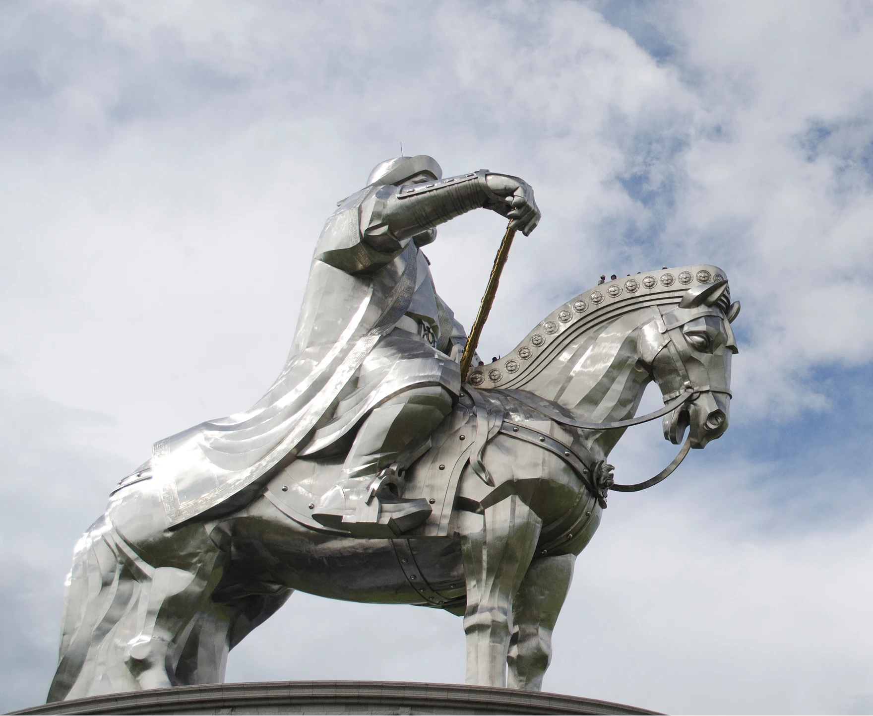 Metallic statue of an armored knight on horseback against a cloudy sky