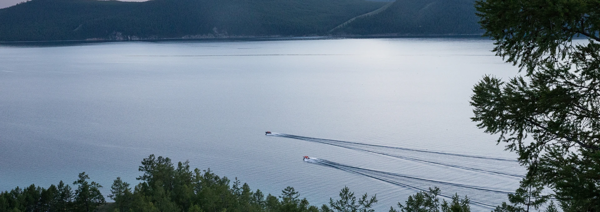 Two boats on a lake with by trees on the shoreline