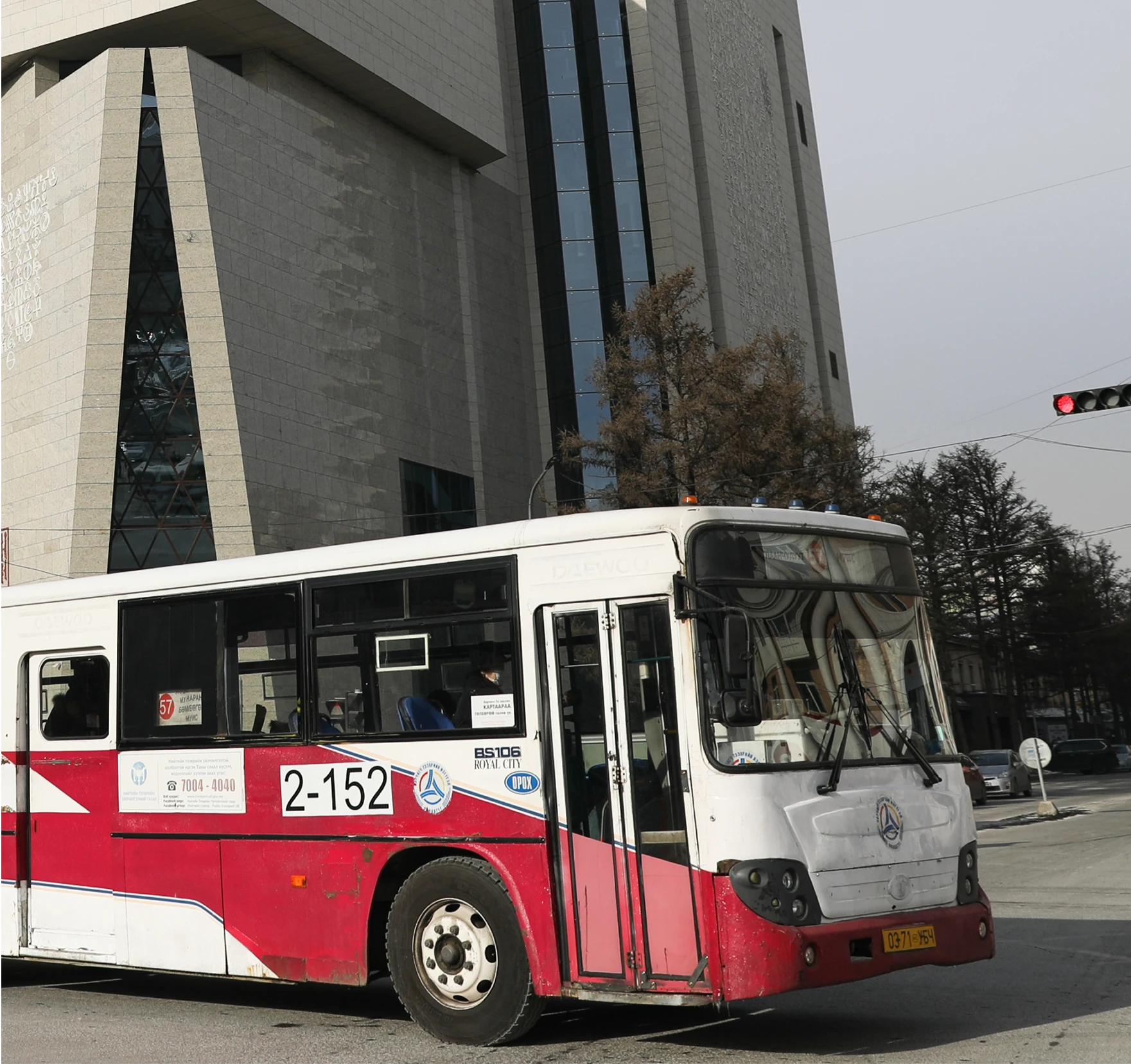 A transport bus on the road with a building in the back.