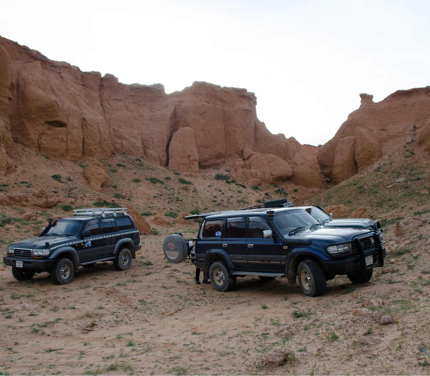 SUV's in a rocky mountainous region with. hills at the back.