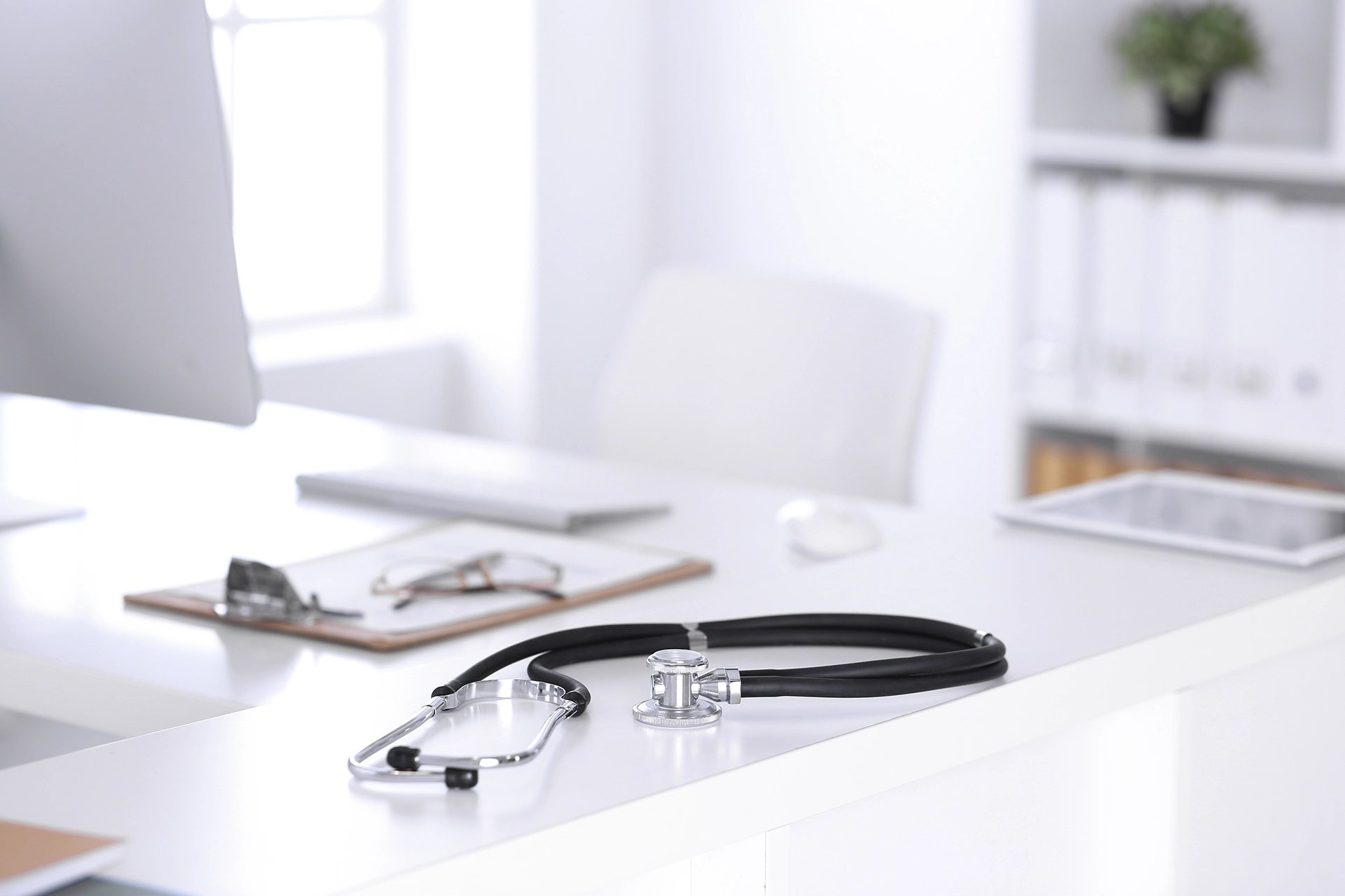 A Stethoscope with a notepad on a table inside an office.